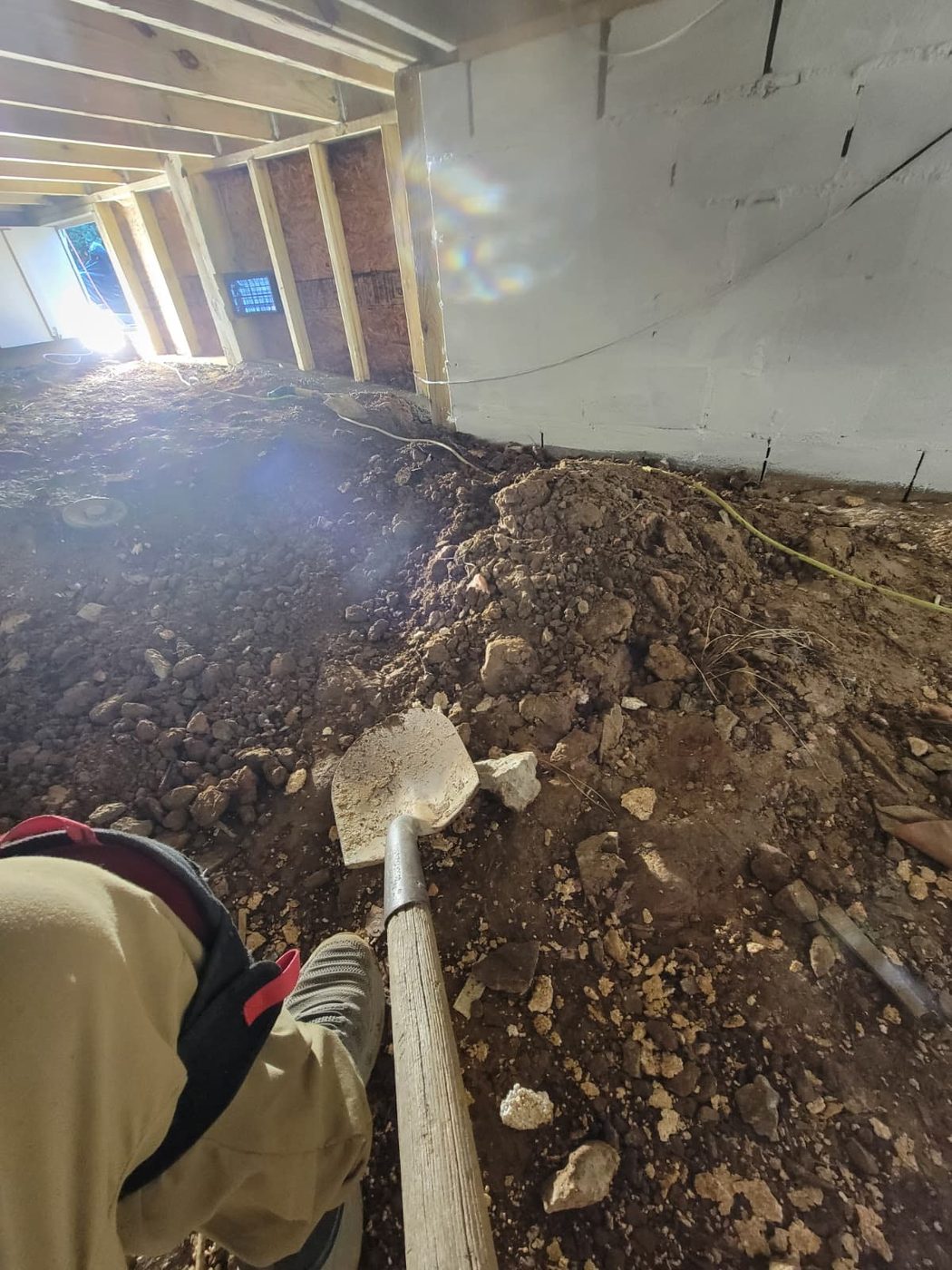 Dirty muddy crawl space with exposed dirt floor before encapsulation