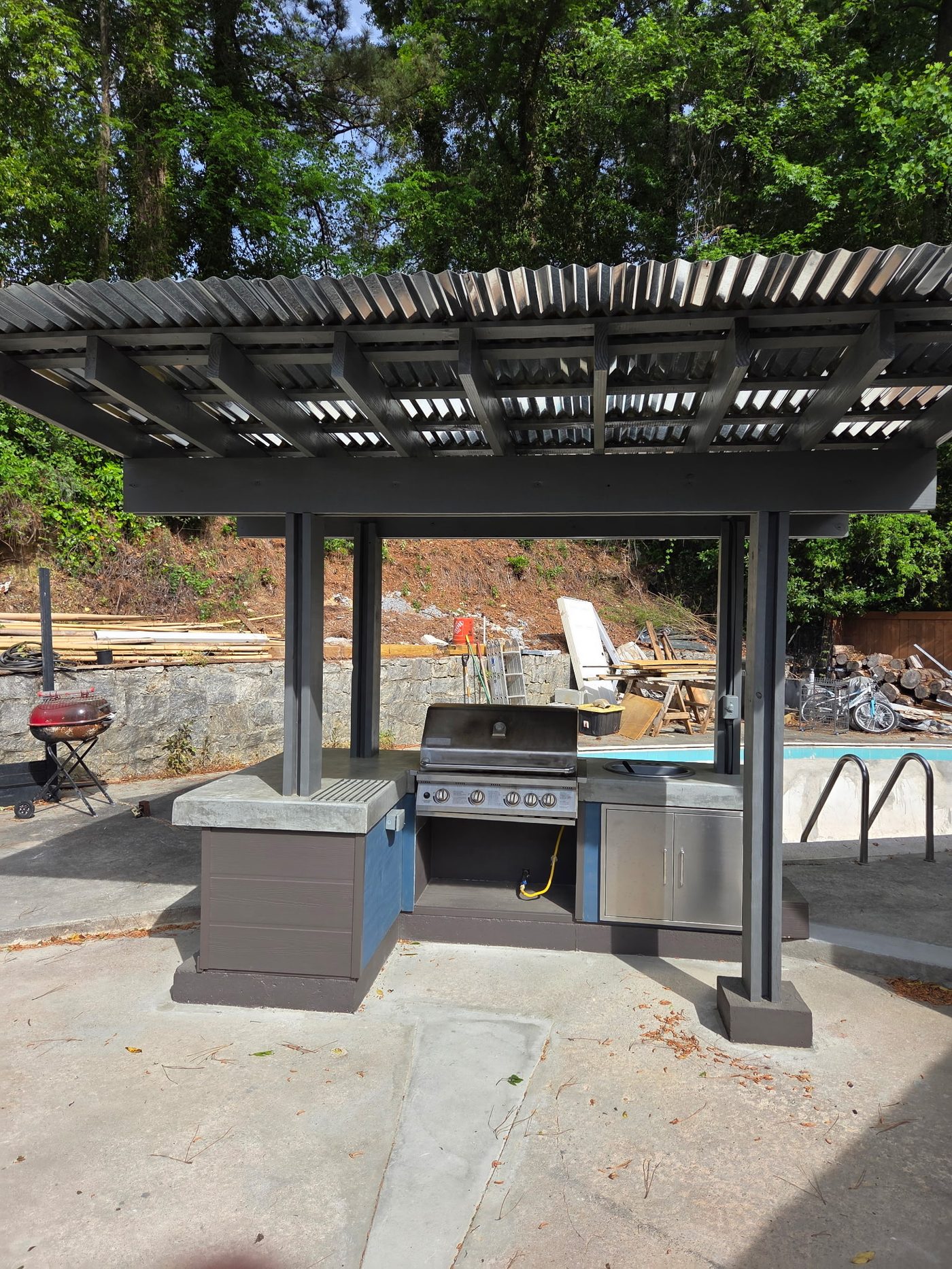 Completed outdoor kitchen with gray pergola, grill and countertop